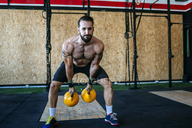 Caucasien sportif homme soulevant kettlebells dans la salle de gym — Photo de stock