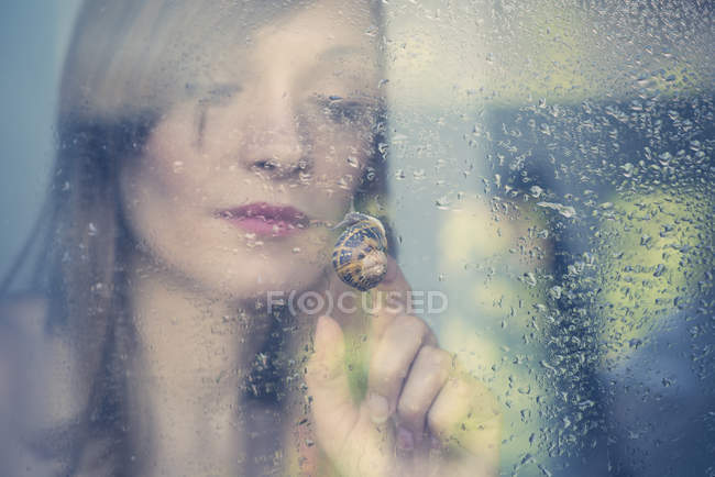 Donna che guarda la lumaca strisciare all'esterno del vetro della finestra — Foto stock