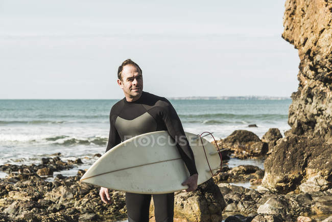Франція, Бретань, Finistere, Crozon півострова, впевнено людина на кам'янистий пляж з дошки для серфінгу — стокове фото