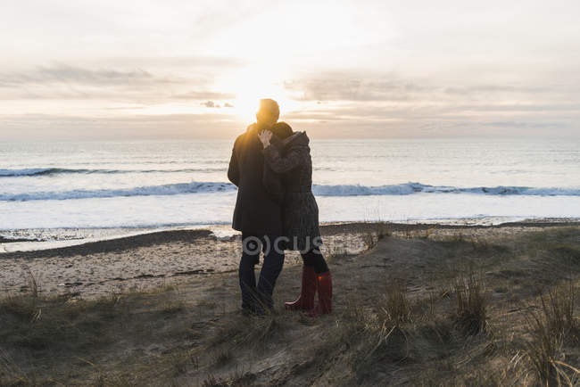 Francia, Bretagne, Finistere, Penisola di Crozon, coppia che si abbraccia sulla costa al tramonto — Foto stock