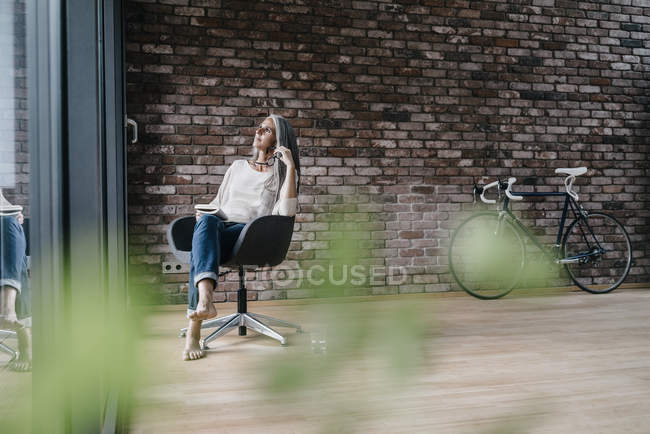 Femme avec de longs cheveux gris assis sur la chaise à la fenêtre — Photo de stock