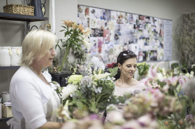 Dos mujeres eligiendo flores en floristería - foto de stock