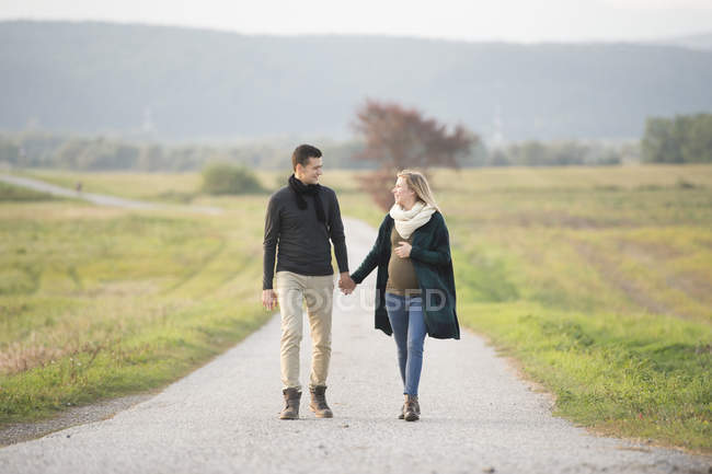 Pais expectantes felizes andando na paisagem rural — Fotografia de Stock