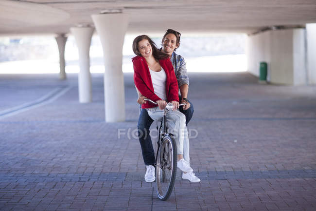 Feliz pareja montando bicicleta en el garaje de estacionamiento - foto de stock