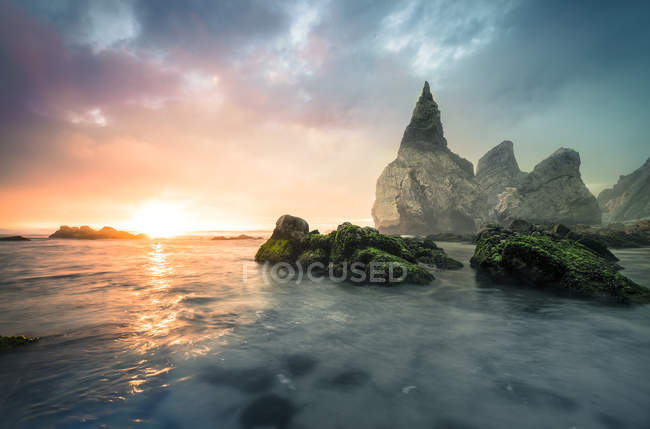 Portugal, Praia Ursa, formações de pedra na praia contra o sol da manhã — Fotografia de Stock
