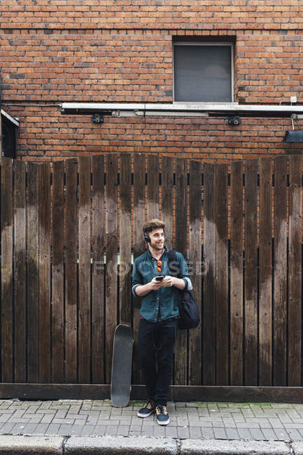 Junger mann mit skateboard und smartphone in dublin, irland — Stockfoto