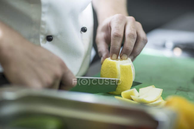 Restaurante chef quitar la cáscara de limón con cuchillo — Stock Photo