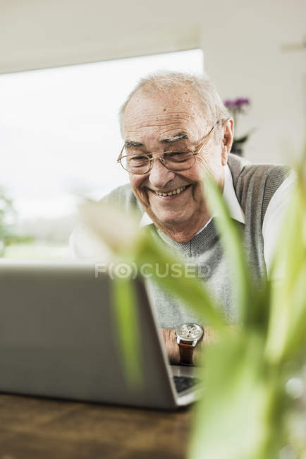 Porträt eines glücklichen Seniors mit Laptop zu Hause — Stockfoto