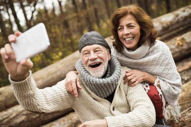 Портрет смеющейся пожилой пары, делающей селфи с помощью мобильного телефона — стоковое фото