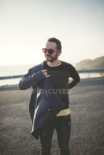 Портрет улыбающегося мужчины в солнечных очках, надевающего пиджак — стоковое фото