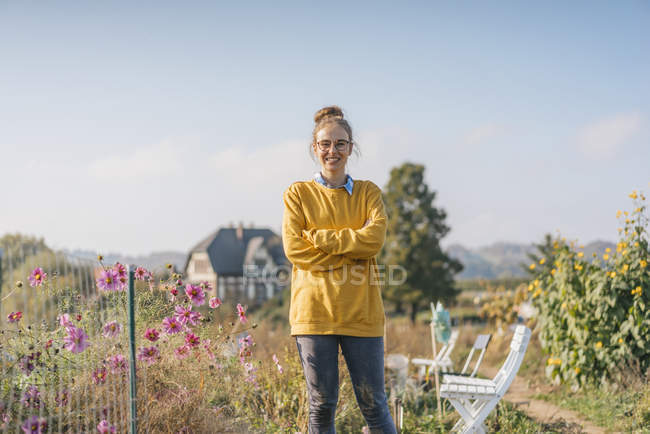 Confident smiling young woman in cottage garden — Stock Photo