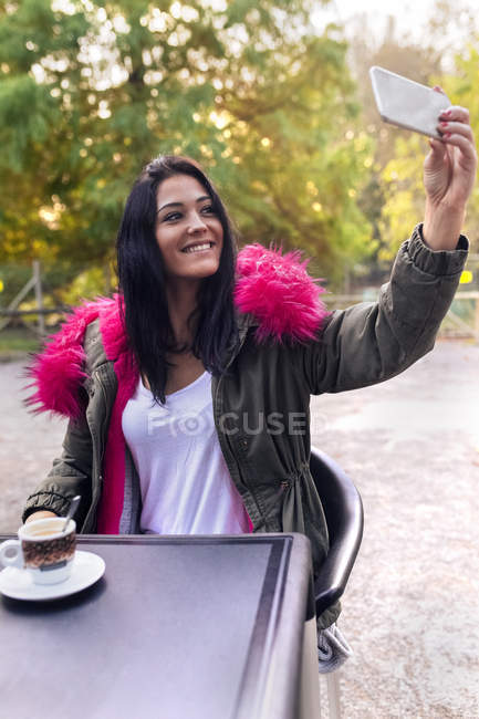 Mujer joven tomando una selfie en un parque en otoño - foto de stock
