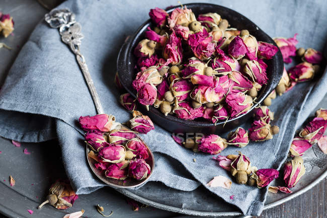 Крупный план цветения сушеной розы в миске и ложке — стоковое фото