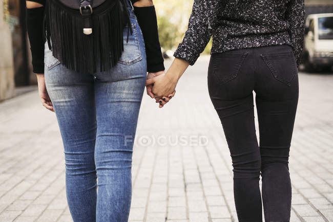 Rückansicht zweier Frauen, die sich auf der Straße an den Händen halten — Stockfoto