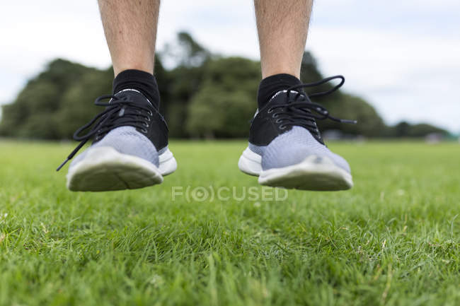 Cropped image of sporty man jumping in park — Stock Photo