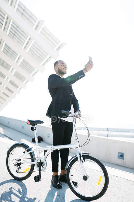 Усміхаючись бізнесмен з велосипеда бере на selfie у місто — стокове фото