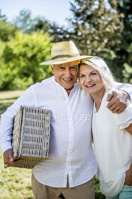 Ritratto di sorridente coppia anziana in piedi con cestino da picnic — Foto stock