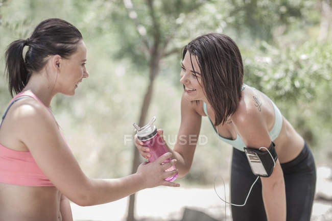 Duas esportistas compartilhando água depois de correr — Fotografia de Stock