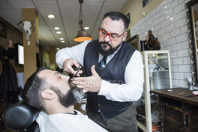 Peluquero barba hombre corte en peluquería salón - foto de stock