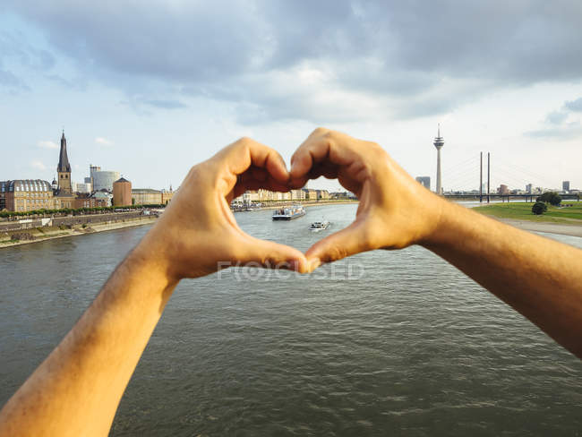 Germania, Duesseldorf, mani che formano un cuore che incornicia le navi sul Reno — Foto stock