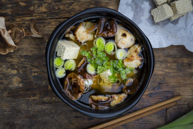 Cuenco de sopa de miso con tofu orgánico, champiñones shitake, puerro y perejil sobre madera oscura - foto de stock