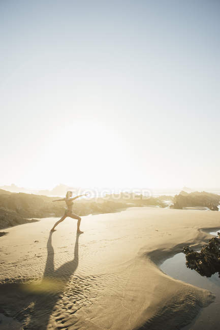 Portugal, Alentejo, Woman practicing yoga at Zambujeira do Mar beach — Stock Photo