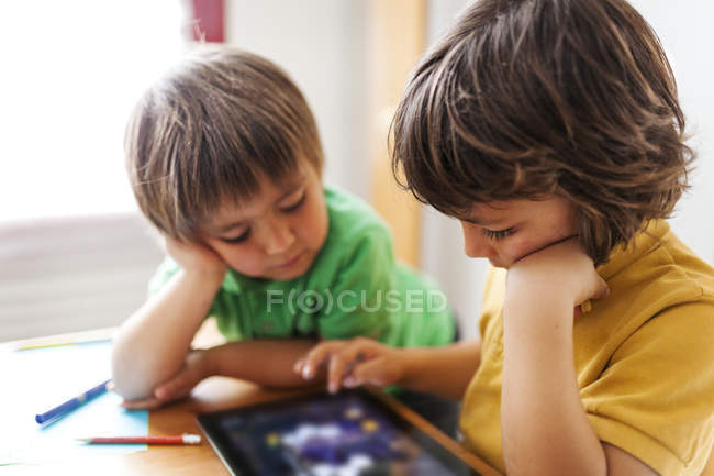 Dos hermanitos jugando con la tableta digital - foto de stock