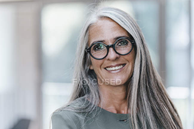 Retrato de mujer sonriente con el pelo largo y gris mirando a la cámara - foto de stock