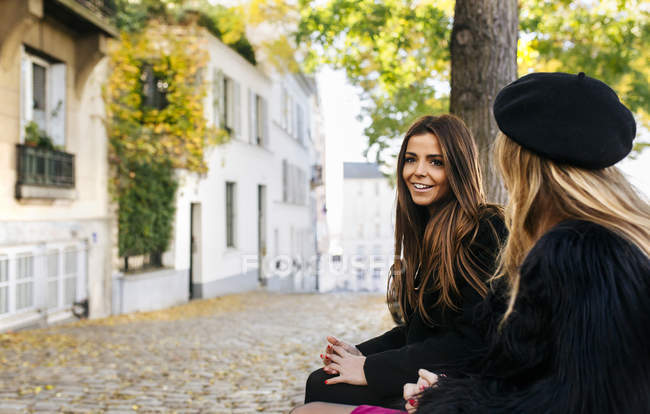 Due giovani donne sedute su una panchina per le strade di Montmartre — Foto stock