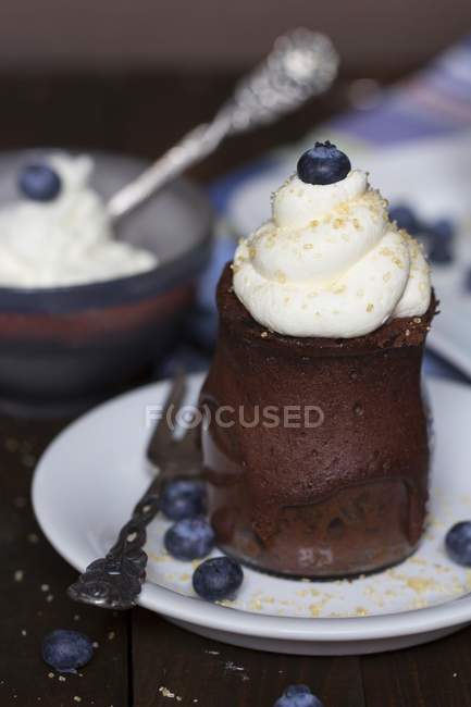 Chocolate cake in a glass with whipped cream, cane sugar and blueberries — Stock Photo
