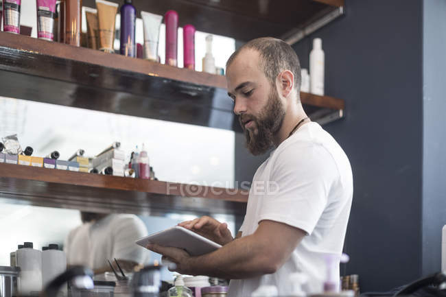 Peluquero haciendo inventario de tienda con tableta digital - foto de stock