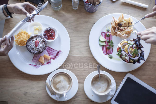 Vista cortada de duas pessoas à mesa com comida e tablet digital — Fotografia de Stock