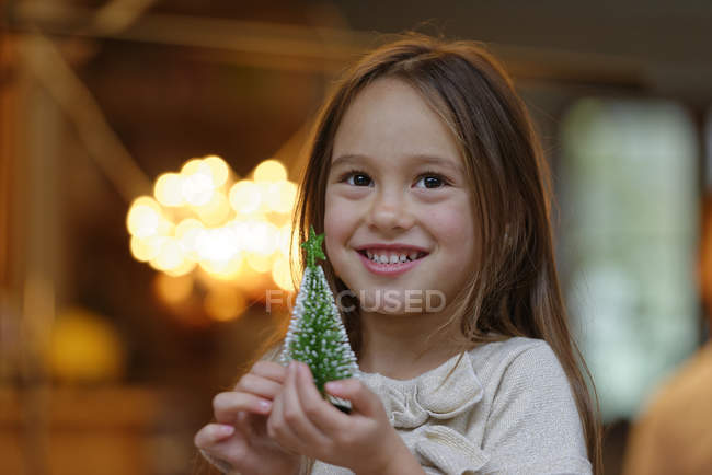 Porträt eines lächelnden kleinen Mädchens mit Miniatur-Weihnachtsbaum — Stockfoto