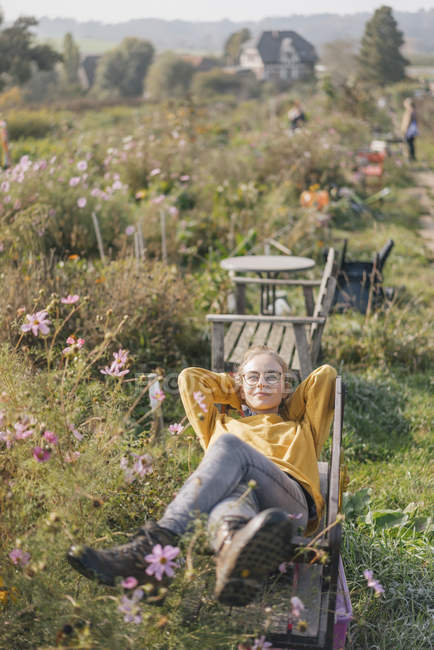 Jeune femme se détendre dans le jardin cottage — Photo de stock