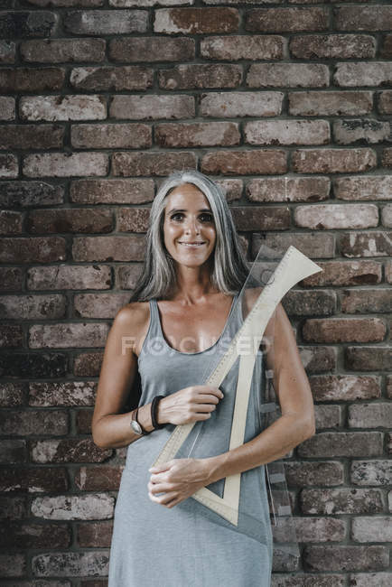 Portrait de femme devant un mur de briques tenant des règles architecturales — Photo de stock