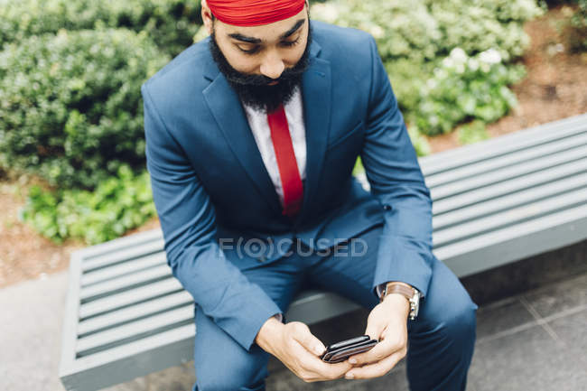 Indischer Geschäftsmann sitzt auf Bank und benutzt Smartphone in manhattan, ny, usa — Stockfoto