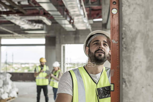 Trabalhador da construção civil que utiliza o nível da água no estaleiro — Fotografia de Stock