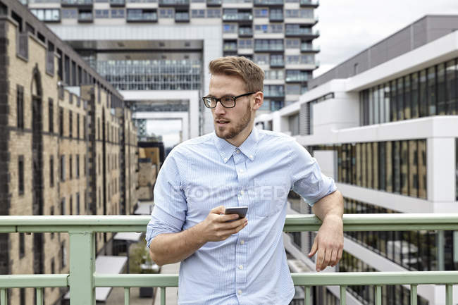 Молодий чоловік з мобільним телефоном стоїть на відкритому повітрі — стокове фото