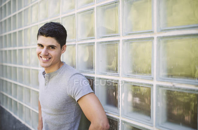 Ritratto di giovane sorridente in piedi davanti al muro — Foto stock