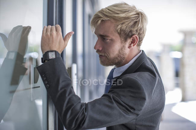 Бизнесмен смотрит через стеклянную дверь — стоковое фото