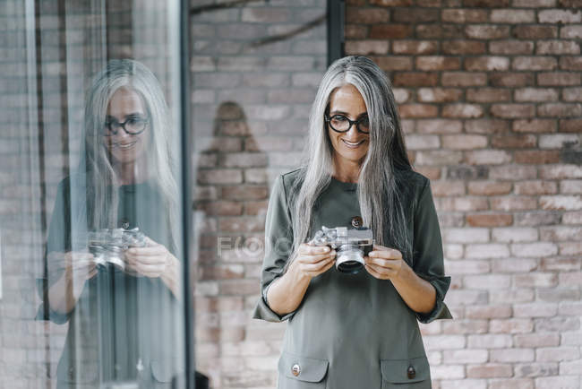 Femme avec longue caméra de maintien des cheveux gris — Photo de stock