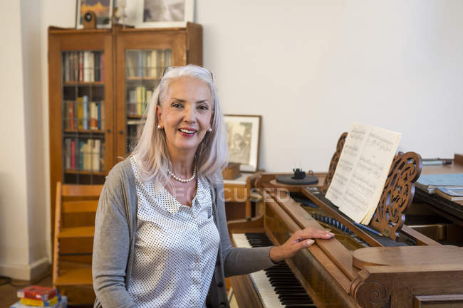 Portrait de femme caucasienne âgée souriante avec piano à la maison — Photo de stock
