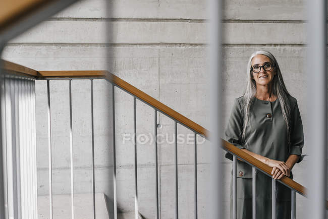 Porträt einer lächelnden Frau mit langen grauen Haaren, die auf der Treppe steht — Stockfoto