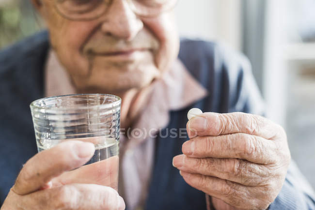 Mani dell'uomo anziano che tiene tablet e bicchiere d'acqua, da vicino — Foto stock