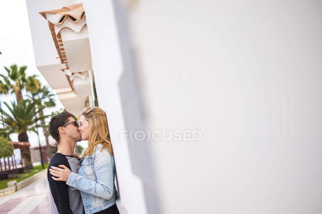 Young couple in love kissing at wall — Stock Photo