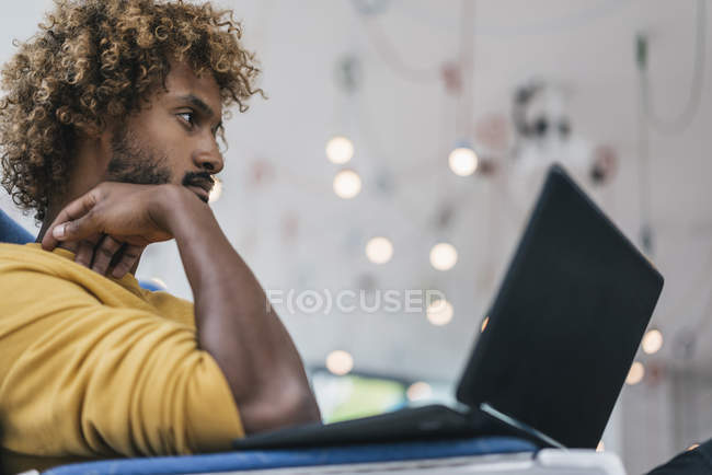 Молодой человек с прической Afro с помощью ноутбука в современном офисе — стоковое фото