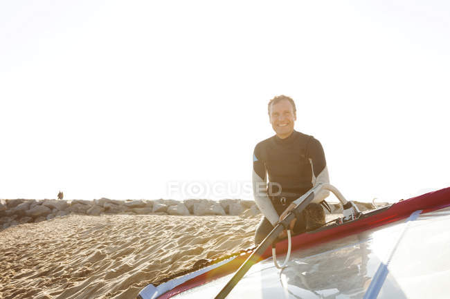 Smiling man on the beach with surfboard — Stock Photo