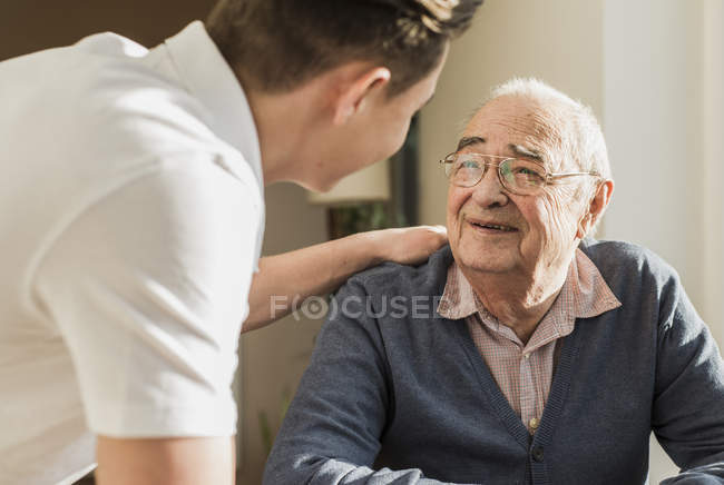Portrait of smiling senior man face to face with his geriatric nurse — Stock Photo