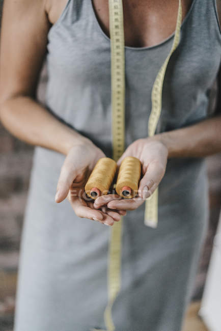 Femme avec ruban à mesurer tenant des bobines de coton — Photo de stock