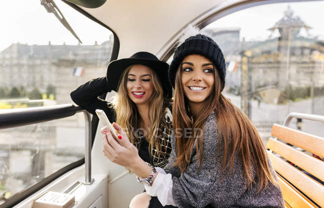 França, Paris, duas mulheres sorridentes com telefone celular em um ônibus turístico — Fotografia de Stock